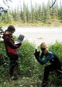 Researchers at the river shore measuring flow discharge